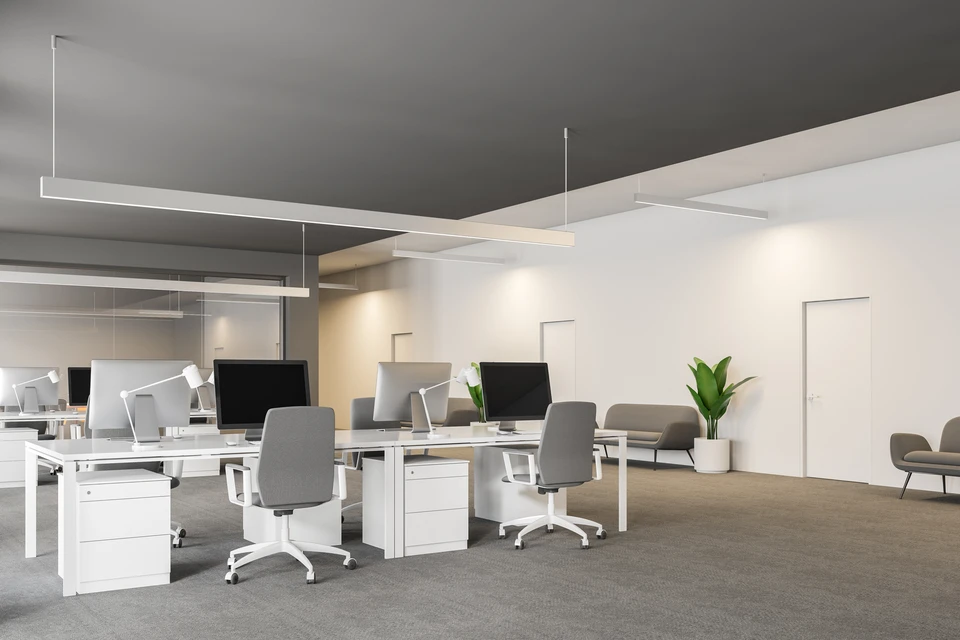 Espace de bureau moderne en open space avec plusieurs postes de travail équipés d'ordinateurs et moniteurs