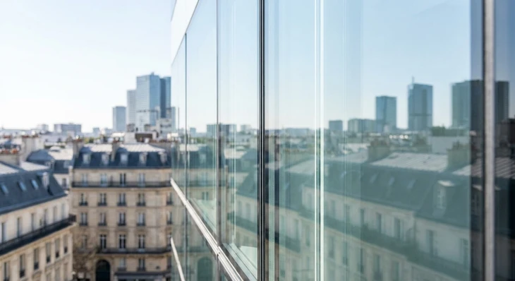 Gros plan professionnel d'une vitre ou baie vitrée immaculée et cristalline, montrant une transparence parfaite sans trace ni résidu. L'image capture la brillance du verre nettoyé, avec des reflets lumineux naturels mettant en valeur la clarté et l'état impeccable de la surface. Le contexte peut être celui d'une façade de bâtiment moderne, d'une baie vitrée de bureau, ou d'une cloison intérieure professionnelle. La profondeur de champ met l'accent sur la qualité et la propreté du verre traité.