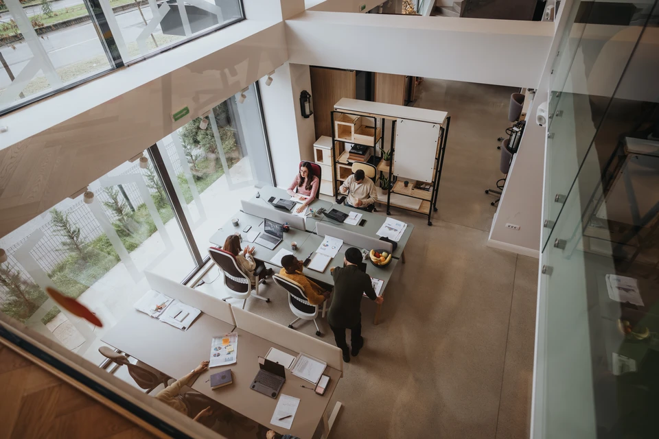Photographie d'un professionnel du nettoyage vêtu de tenue de travail adaptée, effectuant une tâche de maintenance ou de nettoyage dans un bureau ou local professionnel moderne (essuyage de surface, nettoyage de vitres ou organisation d'espace). L'arrière-plan doit montrer un environnement professionnel contemporain. La scène doit communiquer l'idée d'expertise, d'efficacité opérationnelle et de service professionnel externalisé.