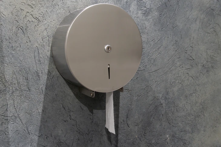 Intérieur de toilettes publiques avec distributeur de papier essuie-mains blanc fixé au mur